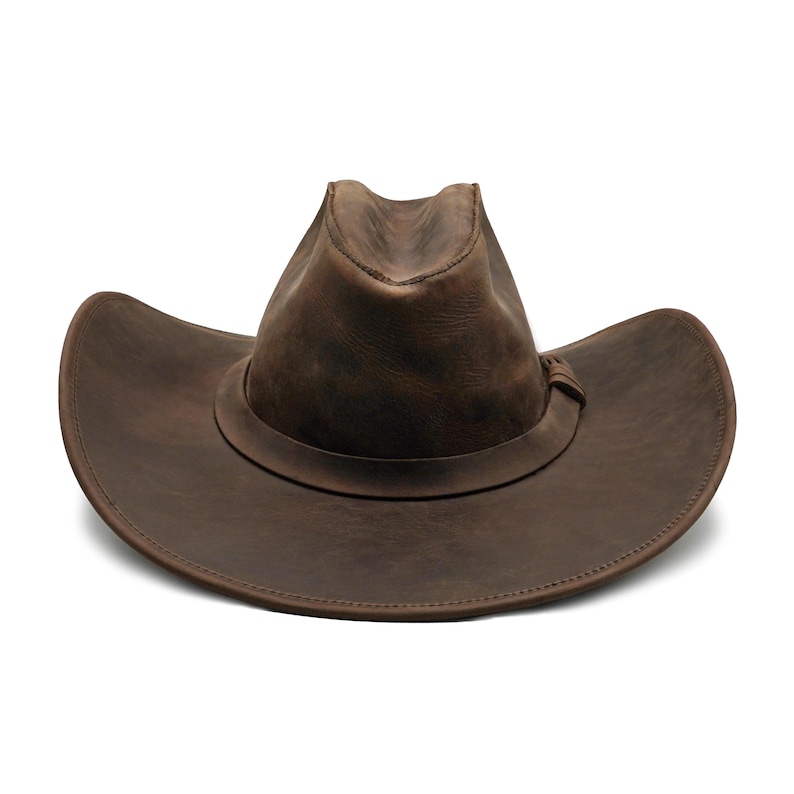 May include: A dark brown leather cowboy hat with a distressed finish, featuring a pinched crown and a wide, curved brim. A matching leather band wraps around the base of the crown, secured with a small, simple leather knot detail on the side.