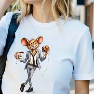 Op de afbeelding: Wit T-shirt met een cartoonmuis in een grijs pak, met een koffiemok met "I RUN THIS" en een chocolate chip cookie. De muis heeft grote oren en een zelfvoldane uitdrukking.