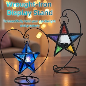 Peut inclure: Présentoirs en fer forgé avec des bougeoirs en forme d'étoile. Une étoile est bleue, l'autre est multicolore avec du verre rouge, violet, vert, jaune et bleu. Le texte dit : « Pour magnifiquement tenir votre lumière de bougie et votre verdure ».
