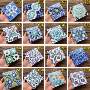 May include: A collection of square ceramic tiles with intricate, colorful patterns. Each tile features a unique design, including floral motifs, geometric shapes, and stylized illustrations in shades of blue, green, and white. The tiles are held in hands.