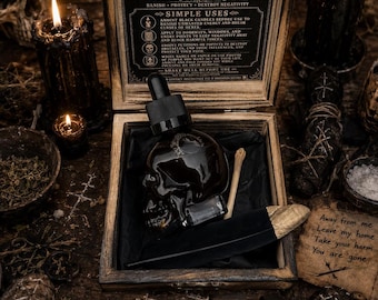 May include: A wooden box containing a skull-shaped glass bottle with a black dropper, a small bone, and a black feather with a gold tip. The box lid features text reading SHAMAN VANQUISHING OIL and instructions. A parchment note reads Away from me.