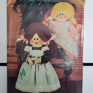 May include: A vintage sewing pattern for making two rag dolls. The pattern is from Butterick and is number 428. The dolls are wearing dresses and have yarn hair. The pattern is priced at $2.00.