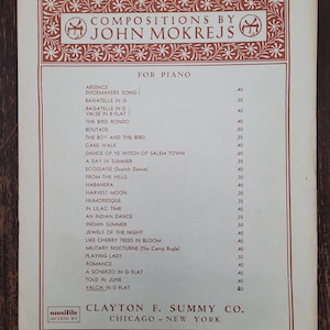 May include: A vintage sheet music cover for piano compositions by John Mokrejs. The cover features a red and white design with a musical note and the title "Compositions by John Mokrejs" in bold, black lettering. The list of compositions includes "Absence", "Shoemakers Song", "Bagatelle in G", "Bagatelle in D", "Valse in B Flat", "The Bird Rondo", "Boutade", "The Boy and the Bird", "Cake Walk", "Dance of Ye Witch of Salem Town", "A Day in Summer", "Ecossaise", "From the Hills", "Habanera", "Harvest Moon", "Humoresque", "In Lilac Time", "An Indian Dance", "Indian Summer", "Jewels of the Night", "Like Cherry Trees in Bloom", "Military Nocturne", "Playing Lady", "Romance", "A Scherzo in G Flat", "Told in June", "Valcik in D Flat". The cover also includes the publisher's information: "Clayton F. Summy Co. Chicago - New York".