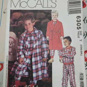 May include: McCall's pattern 6305 featuring children's sleepwear. The cover shows illustrations of children in pajamas and robes. The pajamas are red and white plaid, and the robes are solid red. The pattern includes sizes XSM and SML.