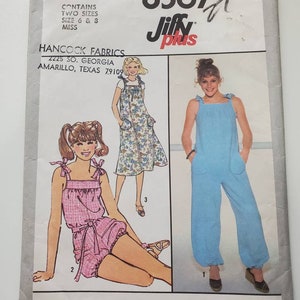 May include: Simplicity pattern 8567 featuring three different jumpsuit and romper designs. The pattern includes sizes 6 and 8. The cover shows illustrations of the garments in pink, floral, and blue fabrics. The pattern is from Hancock Fabrics.