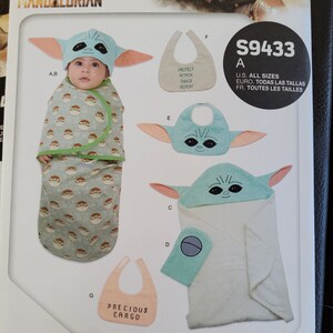 May include: A sewing pattern for baby accessories featuring a character from the Star Wars: The Mandalorian TV series. The pattern includes a hooded towel, a bib, and a sleeping bag. The pattern is labeled "S9433" and includes instructions for all sizes.