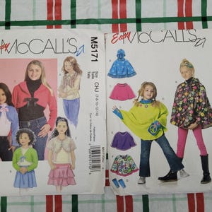 May include: Two sewing pattern packages for children's clothing. The left pattern is for a cropped jacket and the right pattern is for a poncho. Both patterns are from McCall's Easy and feature illustrations of children wearing the garments.