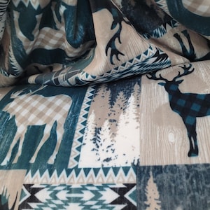 May include: Fabric with a repeating pattern featuring deer, moose, and trees in shades of teal, beige, and white. The deer have plaid patterns. The fabric has a rustic, outdoorsy theme.