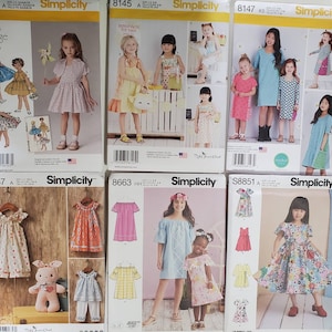May include: A collection of Simplicity sewing patterns for children's dresses. The patterns feature a variety of styles, including vintage, floral, and modern designs. The patterns are printed on white paper with colorful illustrations.