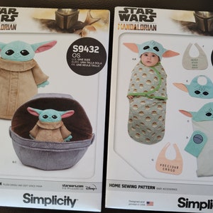 May include: Two Simplicity sewing patterns for Star Wars: The Mandalorian. The left pattern is for a plush Grogu toy and a soft space pram. The right pattern is for a baby hooded towel, a bib, and a sleeping bag. The patterns are numbered S9432 and S9433.