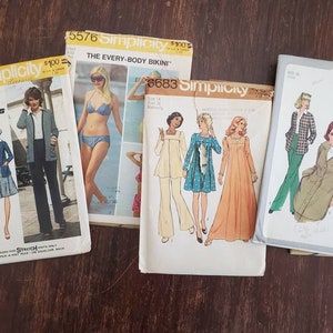 May include: Four vintage sewing patterns for clothing. The patterns are from Simplicity and include a bikini, a dress, a jacket, and a jumpsuit. The patterns are all in different colors and have different models on them.