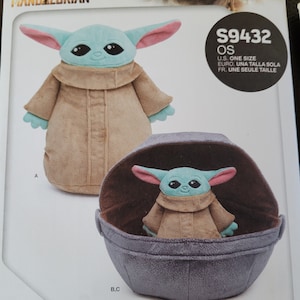 May include: A sewing pattern for a plush Grogu toy and a soft space pram from Star Wars: The Mandalorian. The pattern includes instructions for making a plush toy of the character Grogu, also known as "The Child", and a pram for the toy to sit in. The pattern is labeled "S9432 OS" and includes instructions for making the toy in one size.