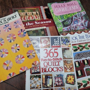 May include: A collection of quilting books with colorful covers. Titles include "Once Upon a Quilt," "For the Season," "Jelly Roll Dreams," "365 Fun-to-Stitch Quilt Blocks," and "Deck the Halls." The books feature various quilt designs and techniques.
