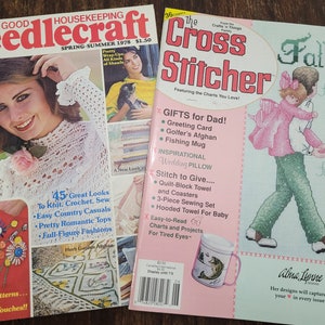 May include: Two vintage magazines, "Needlecraft" and "The Cross Stitcher", featuring cross-stitch patterns and instructions. The "Needlecraft" cover shows a woman wearing a white crocheted top, while the "Cross Stitcher" cover features a cross-stitch design of a father holding a child, with the text "Forever My Hero" and "Forever My Friend".