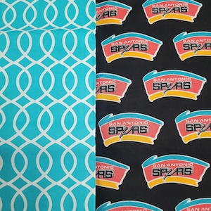 May include: Two fabric patterns are displayed. One features a teal background with a white interlocking oval design. The other is black with a repeating logo of the San Antonio Spurs basketball team in red, white, and yellow.