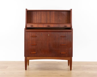 Op de afbeelding: Een donkerbruin houten secretaire met een bovenkast voorzien van een open plank en drie kleine lades. Het onderste gedeelte bevat drie grote lades met horizontale houten handgrepen en een centraal sleutelgat, rustend op vier taps toelopende poten.