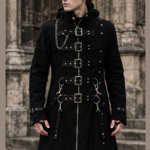 May include: A long black coat with multiple buckles, straps, and metal accents. The coat features a zipper closure, a high collar, and a chain detail. The coat is a gothic or steampunk style.