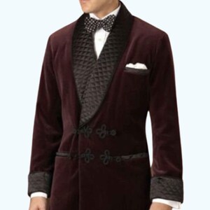 May include: A burgundy velvet blazer with a black quilted lapel and cuffs. The blazer features black frog closures and a white pocket square. A black and white polka dot bow tie is visible.