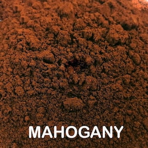 May include: Close-up of a pile of finely ground, dark brown powder. The powder has a textured, granular appearance. The word "MAHOGANY" is displayed in white, bold letters at the bottom of the image.