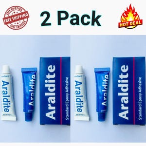 May include: Two packs of Araldite Standard Epoxy Adhesive. Each pack includes a tube and a box with the Araldite logo. The text "2 Pack" is displayed above the products. The image also includes a "Hot Deal" graphic.