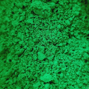 Puede incluir: Primer plano de un mont&oacute;n de polvo verde brillante con una apariencia texturizada y granular. El polvo est&aacute; finamente molido, con peque&ntilde;os grumos y variaciones en la textura. El color es un verde vibrante y saturado.