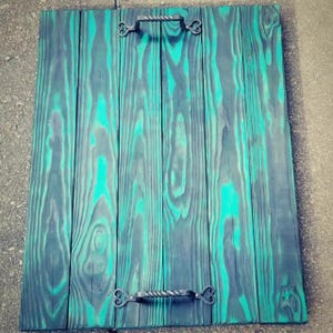 May include: A rectangular wooden serving tray with a teal and grey finish. The tray has a distressed look with visible wood grain and decorative metal handles. The handles are attached with ornate, scrolled brackets. The tray is approximately 46 cm long and 30 cm wide.
