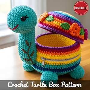 May include: A turquoise crochet turtle box with a rainbow shell and a zipper closure. The turtle's head is detailed with black eyes and a smiling red mouth. The shell is decorated with orange flowers and green leaves. The text "BESTSELLER" is in a red circle.