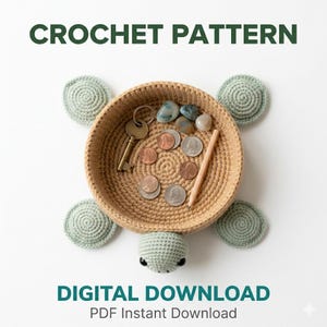May include: A crochet pattern for a turtle-shaped basket. The tan basket has light green crocheted flippers and head. The basket contains coins, a key, small stones, and a pencil. Text at the top reads "CROCHET PATTERN" and at the bottom "DIGITAL DOWNLOAD PDF Instant Download".
