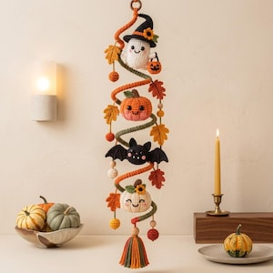 May include: A vertical crochet wall hanging featuring a spiral design with a white ghost in a witch hat, an orange pumpkin, a black bat, and a white pumpkin. The piece is decorated with small crocheted autumn leaves, berries, and a tassel at the bottom.