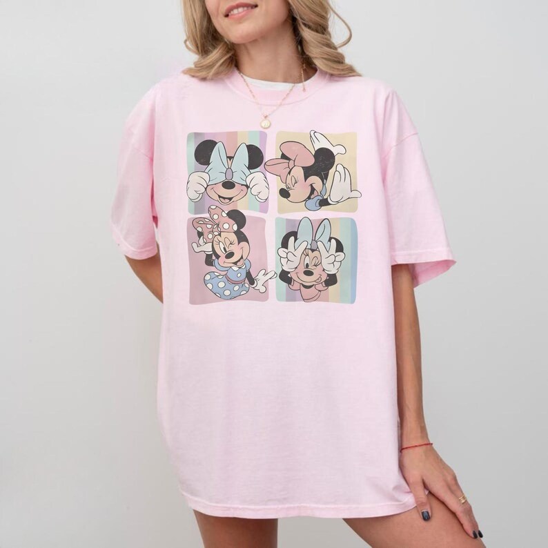 Puede incluir: Una camiseta rosa claro con un gr&aacute;fico de cuatro paneles de Minnie Mouse en varias poses. Cada panel tiene un fondo pastel. La camiseta tiene un corte holgado y de gran tama&ntilde;o.