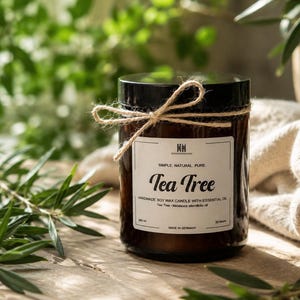 Könnte beinhalten: Eine braune Glas-Kerze mit schwarzem Deckel und weißem Etikett mit der Aufschrift Tea Tree, Simple. Natural. Pure. Handmade soy wax candle with essential oil. Das Glas ist mit einer Juteschnur-Schleife um den Hals gebunden und enthält 200 ml Wachs.
