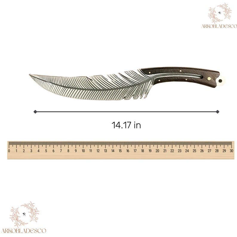 May include: A decorative knife with a feather-shaped blade, measuring 36 cm. The blade is silver-colored with etched feather details. The handle is dark wood with brass accents and a white end piece. The knife is displayed on a white background.