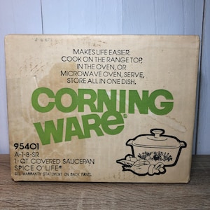 May include: A vintage CorningWare Spice O' Life 1-quart covered saucepan box. The box is tan with green text that reads "Corning Ware" and product details. The box also features a line drawing of the saucepan and vegetables.