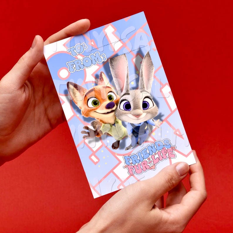 May include: A light blue greeting card featuring cartoon characters Nick Wilde and Judy Hopps from Zootopia. The card has the text "TO: FROM:" at the top and "FRIENDS FUR LIFE" at the bottom. The card is held against a red background.