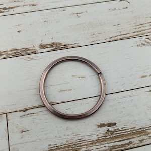 May include: A copper-colored metal key ring with a circular shape.