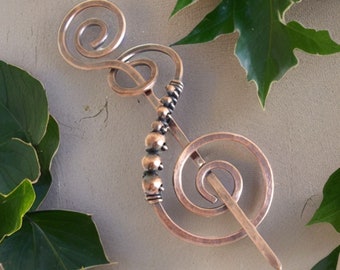 May include: A copper hair pin with a spiral design. The pin is decorated with small copper beads.