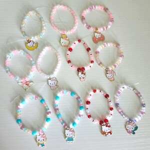 May include: A collection of beaded bracelets in various pastel colors, each featuring a charm of a popular cartoon character. The bracelets are made with small, round beads and are designed for children or those with smaller wrists.