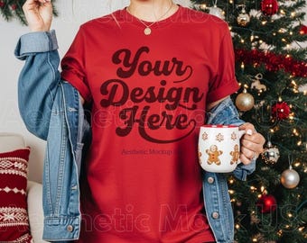 Könnte beinhalten: Ein rotes Kurzarm-T-Shirt mit dem dunkelbraunen Schriftzug Your Design Here in einer Retro-Schriftart, getragen unter einer blauen Jeansjacke. Dazu gehört eine weiße Keramiktasse, die mit braunen Lebkuchenmännchen und Schneeflocken verziert ist.