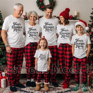 May include: A family wearing matching white t-shirts with the text Your Design Here and red and black buffalo plaid pajama pants. The group includes two adults, two older children, and one young child, with some wearing red Santa hats.