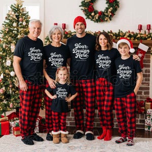 Pode incluir: Uma família de cinco pessoas veste camisetas pretas combinando com o texto Your Design Here e calças de pijama xadrez vermelhas e pretas. O grupo inclui dois adultos, duas crianças e uma criança mais nova, todos em um ambiente festivo.