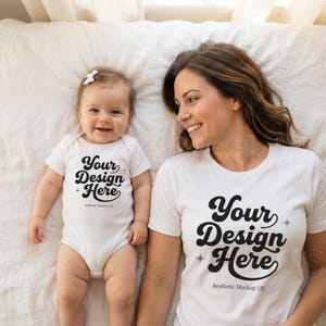 Może przedstawiać: Białe body i koszulka z napisem "Your Design Here" w czarnym skrypcie. Dziecko w body i osoba w koszulce leżą na białej powierzchni. Dziecko ma na sobie białą kokardę.