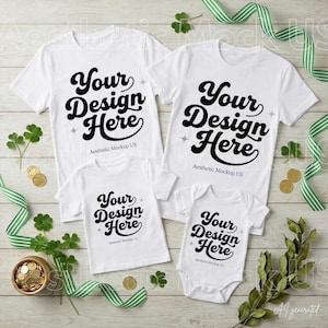 Puede incluir: Dos camisetas blancas y dos prendas de bebé blancas, incluido un body, todas con el texto negro Your Design Here y Aesthetic Mockup US. Los artículos están dispuestos sobre una superficie de madera clara con cintas verdes y monedas de oro.