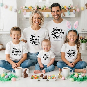 May include: A family of five wearing matching white t-shirts with the black text "Your Design Here" and small star icons. The family consists of two adults, two children, and one baby, all wearing blue jeans. The child on the right wears bunny ears.