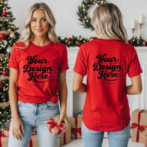 以下が含まれることがあります： 黒い筆記体で「Your Design Here」と書かれた赤いTシャツ。前面と背面の両方が写っています。モデルはブルージーンズを着用しています。このTシャツはカスタムデザインのモックアップです。
