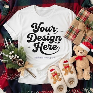 Può includere: Una maglietta bianca con la scritta "Your Design Here" in nero, circondata da oggetti a tema natalizio. Include un regalo confezionato, pantofole a forma di omino di pan di zenzero, un orsacchiotto e pigne.