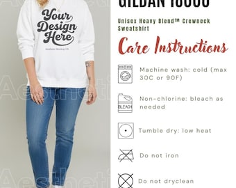 May include: A white crewneck sweatshirt with the black text Your Design Here on the chest, paired with blue jeans and white sneakers. The image includes care instructions for a Gildan 18000 Unisex Heavy Blend sweatshirt, specifying machine wash cold at 90F.