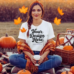 May include: A white t-shirt with the black text Your Design Here and Aesthetic Mockup US printed on the front. The shirt is worn with blue jeans, a brown plaid scarf, and a matching brown headband, while holding a white disposable coffee cup.