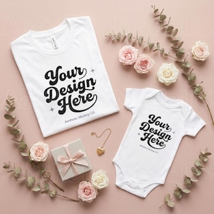 May include: White t-shirt and baby bodysuit mockup with the text "Your Design Here" in black script. The mockup includes a gift box, a gold heart pendant, and roses on a pink background. Aesthetic Mockup US is printed at the bottom.