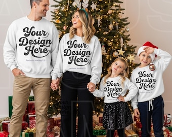 May include: Four people wearing matching white long-sleeve sweatshirts with the black text Your Design Here and Aesthetic Mockup US printed on the front. The group stands in front of a decorated Christmas tree with lights and ornaments.
