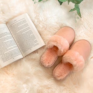May include: Two pairs of soft, fluffy pink slippers with a faux fur lining. The slippers are on a white fluffy rug.